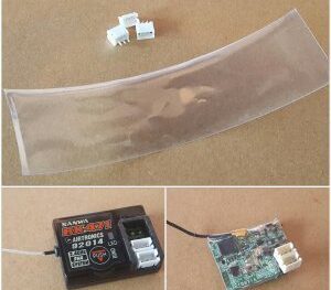De afbeelding toont een set van drie witte JST-connectoren en een stuk transparante krimpkous. Ook is een zwarte ontvanger met het merk Sanwa te zien, samen met een printplaat met een connector.