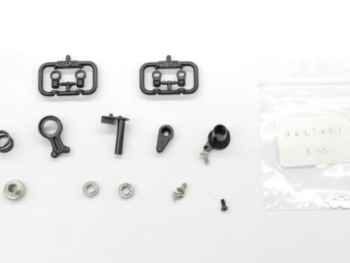 De afbeelding toont een set van kleine, voornamelijk zwarte en zilverkleurige onderdelen voor een modelauto, waaronder plastic sprues, metalen ringen, schroeven en een veer. De onderdelen liggen verspreid op een witte achtergrond, met een klein zakje met shims rechts.