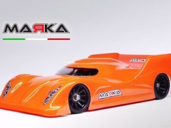 Op de foto is een oranje lexaan raceauto body te zien met zwarte wielen en een 'MARKA' logo. De body heeft een gestroomlijnd ontwerp met een spoiler aan de achterkant.