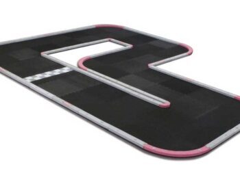 De afbeelding toont een racebaan voor mini-Z auto's, bestaande uit zwarte matten met grijze en roze randen. De baan heeft een complexe vorm met bochten en rechte stukken, en een start/finishlijn.