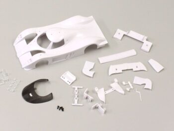 De afbeelding toont een bouwpakket voor een modelauto, voornamelijk bestaande uit witte plastic onderdelen. Er is een grote witte carrosserie en diverse kleinere onderdelen, waaronder enkele transparante en een donkergrijze/zwarte kap.