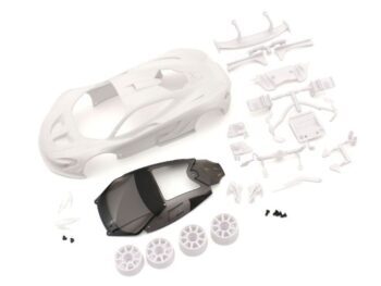 De afbeelding toont een bouwpakket van een witte McLaren P1 GTR carrosserie voor een Mini-Z modelauto, inclusief losse onderdelen zoals wielen, een donker getinte ruit en diverse kleine witte onderdelen en schroefjes.