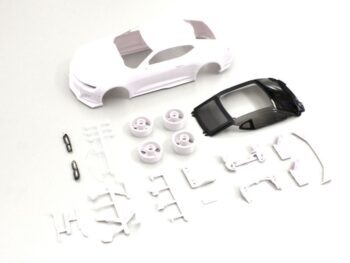 De afbeelding toont een bouwpakket voor een modelauto, bestaande uit een witte carrosserie, een zwart dakdeel, vier witte velgen en diverse kleine witte en zwarte onderdelen. Het geheel ligt verspreid op een witte achtergrond.