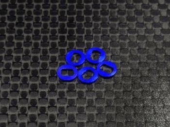 De foto toont vijf blauwe ringvormige onderdelen. Ze liggen op een zwart, geweven oppervlak.