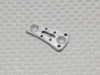 De afbeelding toont een zilverkleurig metalen onderdeel met meerdere gaten en een langwerpige opening in het midden. Het heeft een licht gebogen vorm en ligt op een ondergrond met een ruitpatroon.
