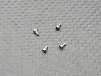 De afbeelding toont vier kleine, zilverkleurige metalen kogelscharnierkoppen, elk met een bolvormig uiteinde en een schroefdraad aan de andere kant. Ze liggen verspreid op een grijze ondergrond met een geweven patroon.