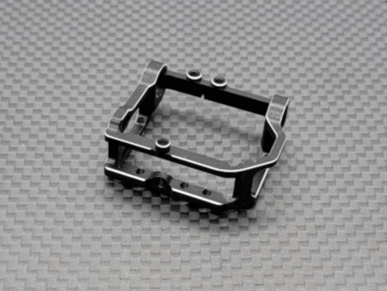 Een zwart metalen motorsteun met zilveren accenten en kleine schroefjes, liggend op een donkergrijze ondergrond met een ruitpatroon. Het product heeft een open, rechthoekige vorm met uitsparingen.