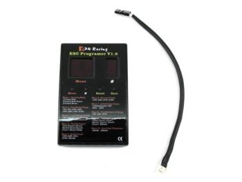 De foto toont een zwart, rechthoekig programmeerapparaat met twee digitale displays en knoppen, vergezeld van een zwarte kabel met een kleine witte connector aan het uiteinde. Op het apparaat staat 'PN Racing ESC Programer V1.0' en diverse menu-opties.