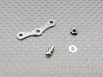 De afbeelding toont een set zilverkleurige metalen onderdelen, waaronder een langwerpig, gebogen stuk met drie gaten, een schroef met een bolvormige kop, een moer en een ring. De onderdelen liggen op een grijze ondergrond met een geweven patroon.