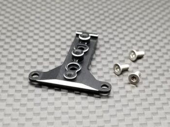 De foto toont een zwart, langwerpig metalen onderdeel met meerdere gaten en een zilverkleurige rand, samen met drie kleine zilverkleurige schroeven. Het geheel ligt op een donkergrijze ondergrond met een ruitpatroon.