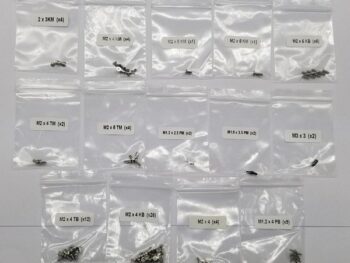 De afbeelding toont een verzameling kleine, zilverkleurige schroeven, gesorteerd in individuele doorzichtige plastic zakjes. Elk zakje is voorzien van een wit etiket met daarop de specificaties en het aantal schroeven.