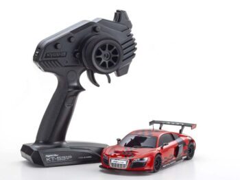 De foto toont een rode modelauto met zwarte details en een zwarte afstandsbediening. De auto heeft een sportief ontwerp met een achtervleugel.