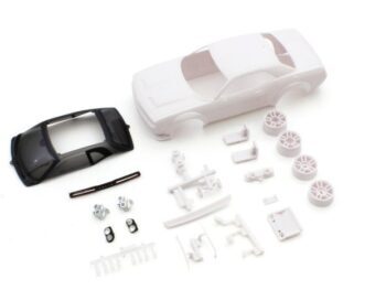 De afbeelding toont een bouwpakket van een witte Dodge Challenger SRT carrosserie voor een mini-Z modelauto, inclusief een transparant zwart dak, witte velgen en diverse kleine onderdelen. De onderdelen liggen verspreid op een witte achtergrond.