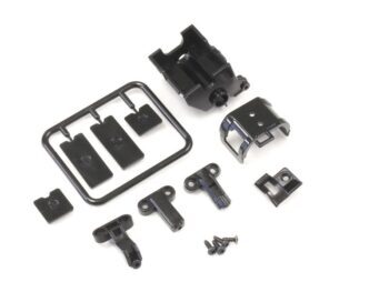 De afbeelding toont een set zwarte plastic onderdelen voor een modelauto, waaronder een motorsteun en diverse kleine bevestigingsonderdelen, deels nog aan een spruw. Er zijn ook enkele kleine schroefjes zichtbaar.
