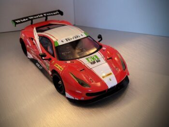 Op de foto is een rode raceauto te zien met witte en groene accenten en diverse sponsorlogo's. Het is een gedetailleerde miniatuurversie van een Ferrari 488 GT3 met een grote achterspoiler.