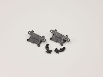 Op de foto zijn vier zwarte kunststof onderdelen te zien, waaronder twee grotere, rechthoekige platen met gaten en twee kleinere, gebogen onderdelen. Op de grotere onderdelen staat 'Kyosho' in reliëf.