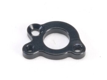 La photo montre une pièce métallique noire de forme irrégulière et arrondie. Elle comporte un grand trou rond au centre et trois trous plus petits sur les bords, dont l'un est fileté.