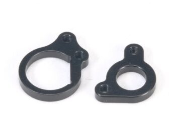 La photo montre deux pièces métalliques noires dotées de trous de vis et d'une ouverture ronde au centre. Il semble s'agir de plaques de fixation du moteur pour une voiture télécommandée.