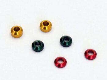 De afbeelding toont zes kleine, ringvormige metalen spacers in de kleuren goud, groen en rood, verspreid over een witte achtergrond.