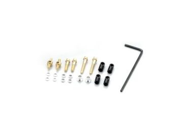 De foto toont een set kleine metalen onderdelen, waaronder gouden schroeven, zilverkleurige ringen en zwarte busjes, samen met een zwarte inbussleutel. De onderdelen liggen verspreid op een witte achtergrond.