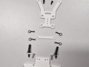 De afbeelding toont een set van diverse onderdelen voor een modelauto, waaronder witte plastic beugels, zwarte body clips, zwarte en zilveren schroeven, en een zwart schuimrubberen onderdeel. De onderdelen liggen geordend op een lichtgrijze ondergrond.