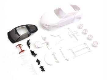The image shows a model car construction kit, consisting of a white body, a dark interior, white rims and various small parts in white, black and red. The whole thing is scattered on a white background.