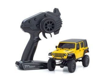 De afbeelding toont een gele Jeep Wrangler Rubicon RC-auto met een zwarte afstandsbediening ernaast. De auto heeft een gedetailleerd uiterlijk met zwarte accenten en off-road banden.