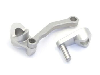 The image shows two silver-coloured metal parts, probably made of aluminium, with a complex, curved shape and holes for mounting. They resemble mechanical arms or levers.