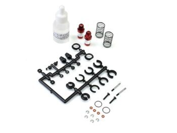 De foto toont een set onderdelen voor schokdempers, waaronder zwarte plastic onderdelen op een sprue, rode schokdemperbehuizingen, zilverkleurige veren, een flesje olie en diverse kleine metalen onderdelen zoals schroeven en ringen.