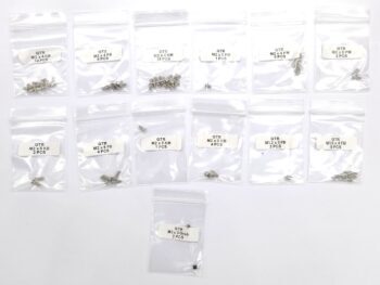 De afbeelding toont een verzameling kleine, zilverkleurige schroeven en een paar zwarte schroeven, verpakt in individuele doorzichtige plastic zakjes met witte labels. De labels geven 'GTR' en de specificaties van de schroeven aan.