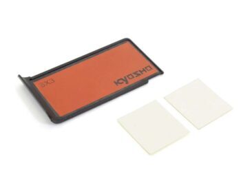 The image shows a rectangular, black frame with an orange-brown area in the centre, on which 'KYOSHO' is written. Next to it are two square, white slices.