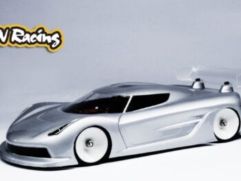De foto toont een zilverkleurige auto body met een spoiler. De body is gemaakt van een doorzichtig materiaal en heeft witte wielen.