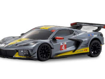 De foto toont een gedetailleerde modelauto, een Chevrolet Corvette C8-R, in een gun metal grijze kleur met gele en rode accenten. Het is een race-uitvoering met een grote achterspoiler en racestickers.