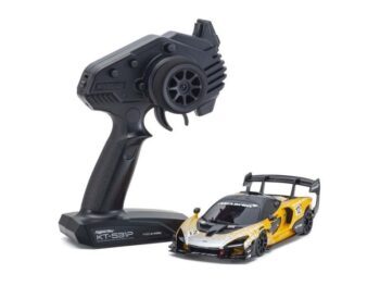 De foto toont een kleine modelauto met een zwarte afstandsbediening. De auto is voornamelijk geel met zwarte details.