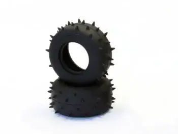 The image shows two black rubber tyres with pointed studs on the outside, stacked on top of each other. They appear to be suitable for off-road use.
