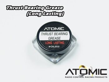 Op de foto is een klein, doorzichtig vierkant potje te zien met een zwarte deksel. Op de deksel zit een wit etiket met zwarte en rode tekst, waaronder 'ATOMIC' en 'THRUST BEARING GREASE'.