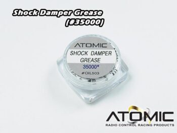 Een klein, transparant plastic potje met een zilverkleurig etiket waarop 'ATOMIC SHOCK DAMPER GREASE' staat. Het potje bevat een witte substantie.