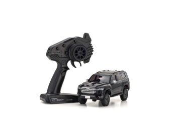 Op de foto is een zwarte, gedetailleerde modelauto te zien, een Toyota Land Cruiser 300, naast een zwarte afstandsbediening. De auto heeft een robuuste uitstraling met dakrails en terreinbanden.