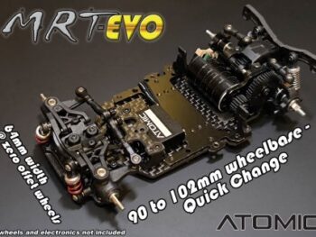 De foto toont een zwart chassis van een RC-auto, gemaakt van koolstofvezel en metaal. Het chassis heeft gedetailleerde ophanging en aandrijfcomponenten, met rode accenten op de schokdempers.
