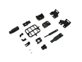 De afbeelding toont een set zwarte plastic onderdelen voor een RC-auto. De onderdelen variëren in vorm en grootte, waaronder een frame met ringen, een schokdemper-achtige component en diverse kleine bevestigingsstukken.