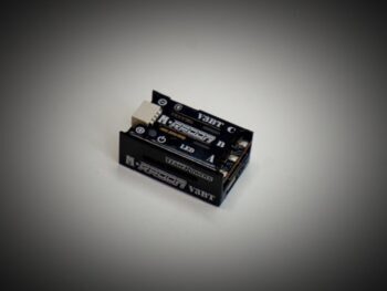 Le produit est un régulateur électronique noir orné d'un texte et de logos blancs. Il présente une forme rectangulaire compacte avec des composants visibles sur le côté.
