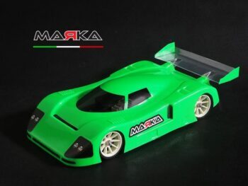 De foto toont een groene auto body voor een modelauto, met een transparante vleugel. De body is van plastic en heeft het merklogo van Marka Racing.