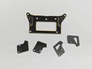 De foto toont een set zwarte platen met gouden accenten, vermoedelijk gemaakt van metaal of carbon. Er zijn verschillende vormen en maten te zien, waarschijnlijk onderdelen voor een modelauto.