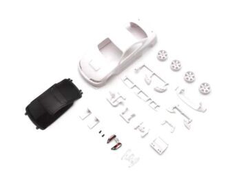 De foto toont een witte auto body, samen met diverse witte onderdelen en een zwarte dak. Er zijn ook wielen en andere accessoires aanwezig.