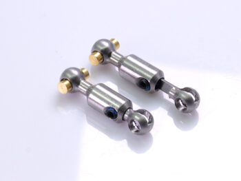 De foto toont twee zilverkleurige dogbones met gouden details. De dogbones zijn gemaakt van metaal en hebben een complexe vorm met kogelgewrichten.