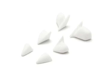 De foto toont een aantal witte, kleine, onregelmatig gevormde objecten. Het lijken kleine onderdelen te zijn, mogelijk van plastic of hars.