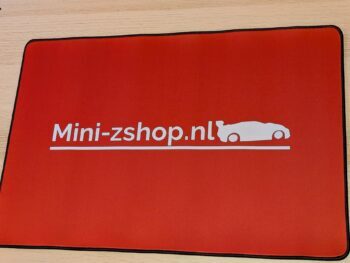 De foto toont een rode pitmat met een witte opdruk van 'Mini-zshop.nl' en een auto-silhouet. De mat heeft een zwarte rand.