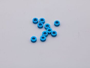 De foto toont een aantal kleine, blauwe ringen. Ze lijken van metaal te zijn en hebben een gat in het midden.