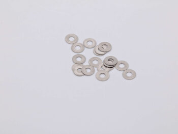 De foto toont een verzameling zilverkleurige ringen, vermoedelijk shims, verspreid over een witte achtergrond. De ringen zijn van metaal en hebben een gat in het midden.
