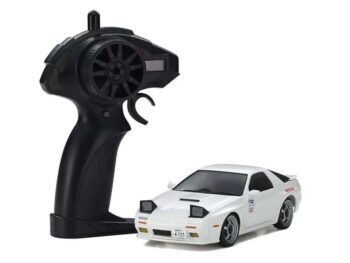 De foto toont een witte modelauto met zwarte details en een zwarte afstandsbediening. De auto heeft een sportief ontwerp en staat naast de afstandsbediening op een witte achtergrond.